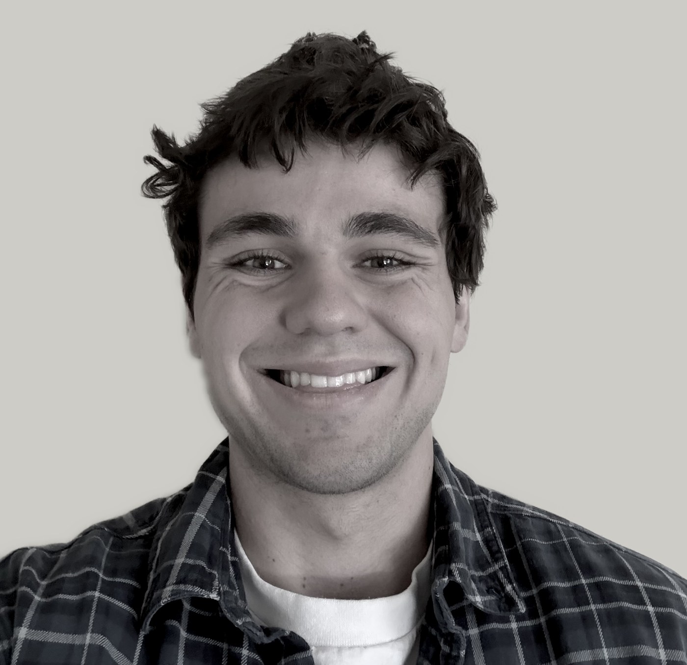 Brayden Sanford smiling, wearing a plaid flannel shirt over a white T-shirt