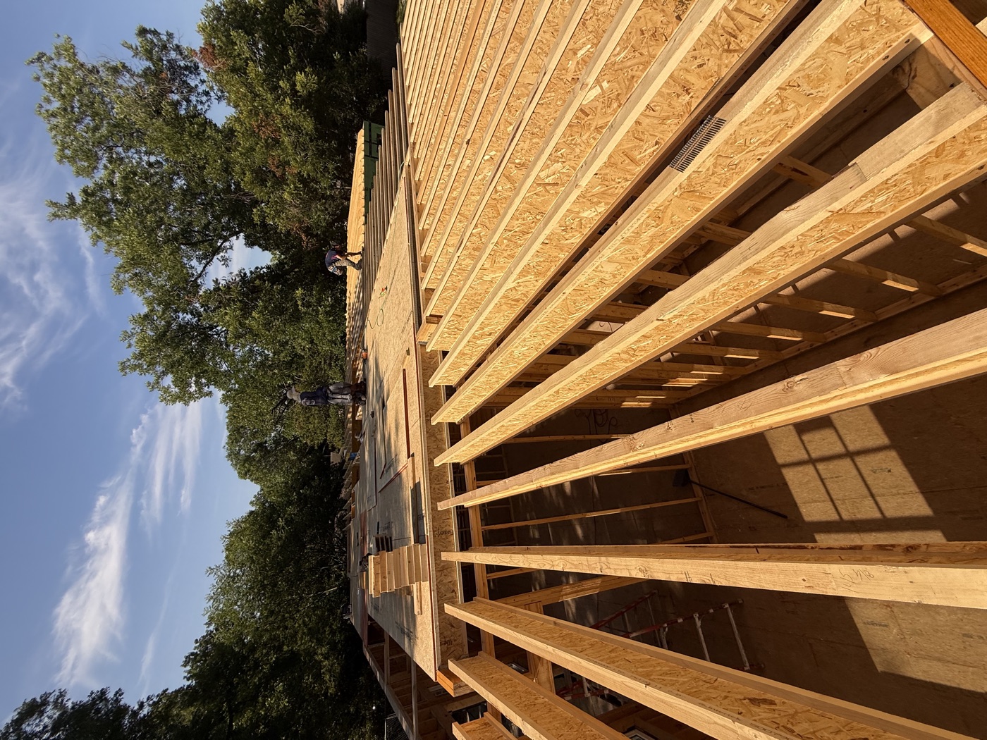 Engineered I-joists set across new framed walls while the crew lays subfloor for the second story